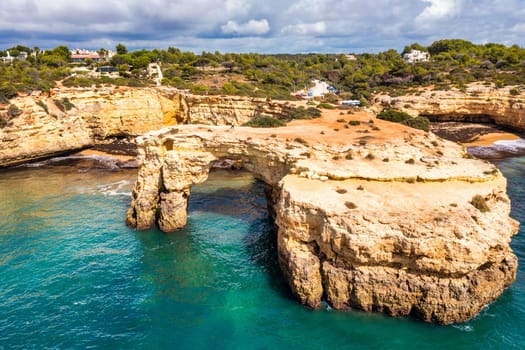 Natural arch above ocean, Arco de Albandeira, Algarve, Portugal. Stone arch at Praia de Albandeira, Lagoa, Algarve, Portugal. View of the natural arch Arco da Albandeira in the Algarve, Portugal.