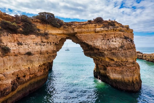Natural arch above ocean, Arco de Albandeira, Algarve, Portugal. Stone arch at Praia de Albandeira, Lagoa, Algarve, Portugal. View of the natural arch Arco da Albandeira in the Algarve, Portugal.