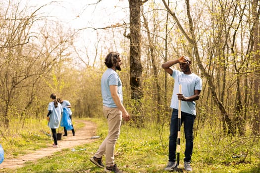 Team of people doing voluntary work to grow trees in the forest, covering holes in the ground with more vegetation for reforestation. Contributing to nature conservation mission.