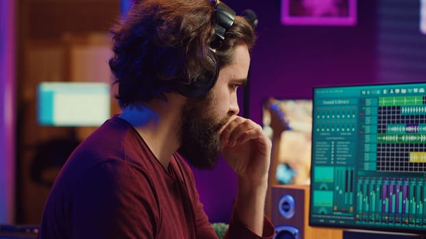 Music producer engages in post production with editing and time aligning recorded songs. Musician using digital audio workstations to manipulate tunes, adding audio effects. Camera A.