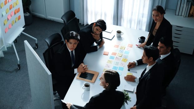 Top view of business people brainstorm idea by using sticky notes while planning marketing strategy at meeting room. Group of diverse team discuss about financial plan. Teamwork concept. Directorate.