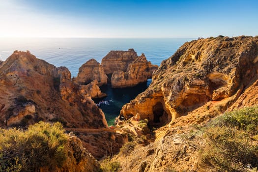 Panoramic view, Ponta da Piedade near Lagos in Algarve, Portugal. Cliff rocks and tourist boat on sea at Ponta da Piedade, Algarve region, Portugal. Ponta da Piedade, Algarve region, Portugal.