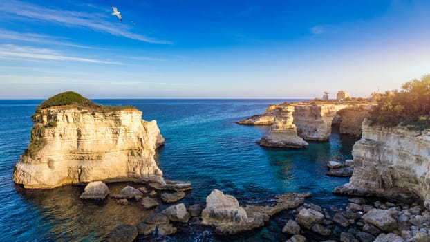 Stunning seascape with cliffs rocky arch and stacks (Faraglioni) at Torre Sant Andrea, Salento coast, Puglia region, Italy. Beautiful cliffs and sea stacks of Sant'Andrea, Salento, Apulia, Italy