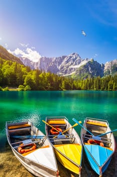 Picturesque lake Lago Fusine with colorful boats. Fusine lake with Mangart peak on background. Popular travel destination of Julian Alps. Location: Tarvisio comune , Province of Udine, Italy, Europe.