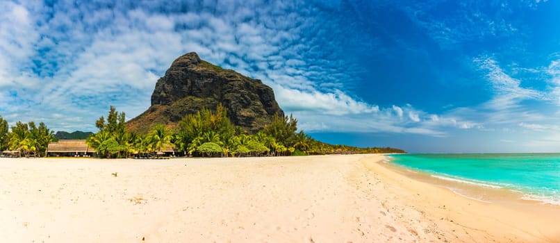 Beach with palm trees and umbrellas on Le morne beach in Mauriutius. Luxury tropical beach and Le Morne mountain in Mauritius. Le Morne beach with palm trees, white sand and luxury resorts, Mauritius