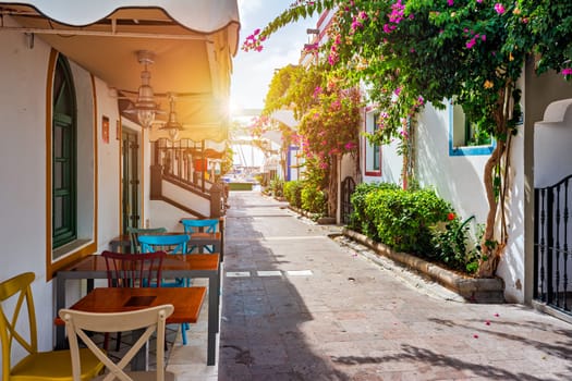 Street with blooming flowers in Puerto de Mogan, Gran Canaria, Spain. Favorite vacation place for tourists and locals on island. Puerto de Mogan with lots of bougainvillea flowers, Canary Island.