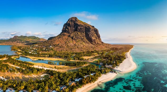 Beach with palm trees and umbrellas on Le morne beach in Mauriutius. Luxury tropical beach and Le Morne mountain in Mauritius. Le Morne beach with palm trees, white sand and luxury resorts, Mauritius