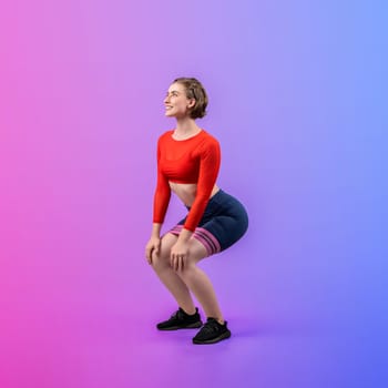 Full body length gaiety shot athletic and sporty young woman with fitness elastic resistance band in squat exercise posture on isolated background. Healthy active and body care lifestyle.