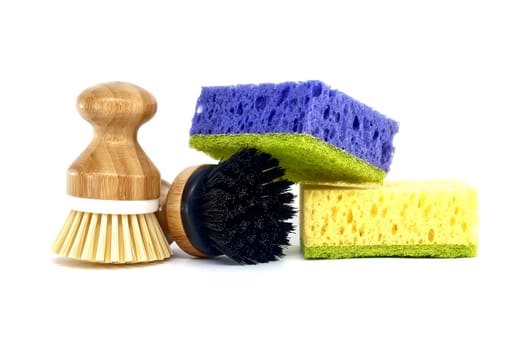 Sponges, each a different color purple, yellow and two brushes with wooden handles isolated on white background, cleaning tools