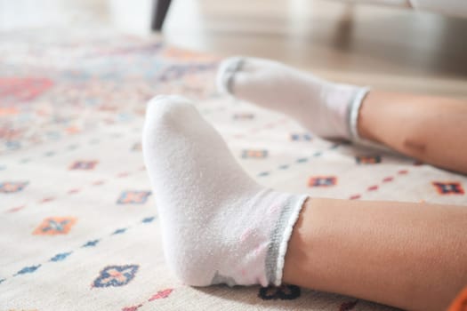 a white soft socks on child feet on carpet