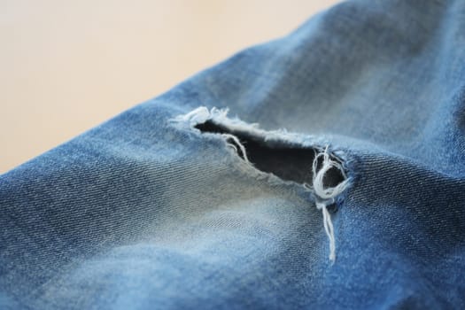 blue jean texture with a hole and ripped threads showing.