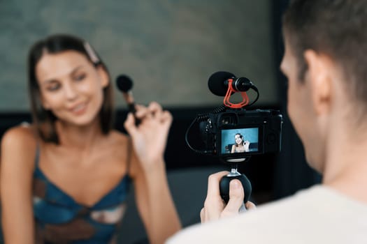 Man filming video on young woman making beauty and cosmetic tutorial video content for social media. Beauty blogger smiles to camera while showing how to beauty care to audience or follower. Unveiling