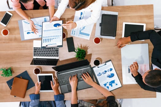 Top view of businessman executive in group meeting with other businessmen and businesswomen in modern office with laptop computer, coffee and document on table. People corporate business team uds