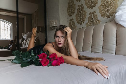 A woman is laying on a bed with a rose and a leaf on her lap. Concept of relaxation and tranquility, as the woman is in a comfortable position and surrounded by natural elements