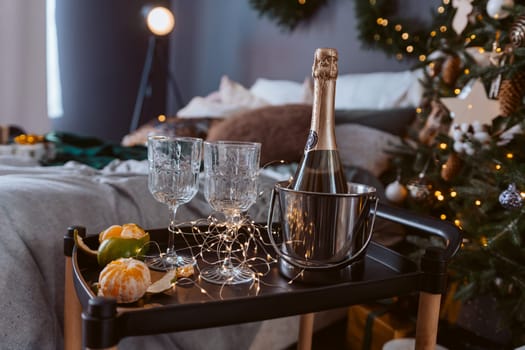 A tray with a bottle of champagne, two wine glasses, and fruit. Scene is celebratory and festive