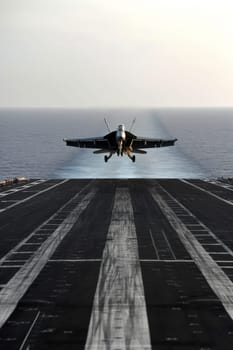 Jet fighter ascends from the aircraft carrier's runway into a clear sky