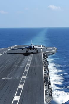 Fighter jet accelerating for departure on the runway of an aircraft carrier at sea