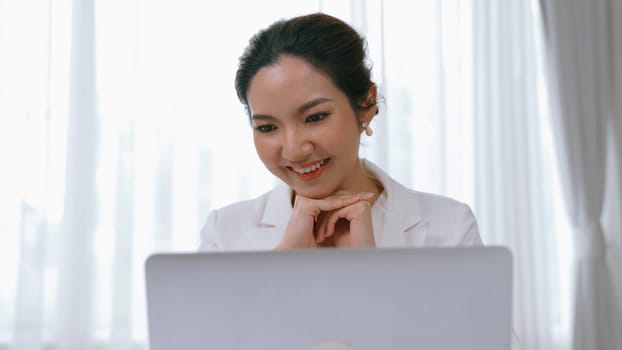 Young businesswoman sitting on the workspace desk using laptop computer for internet online content writing or secretary remote working from home. Vivancy