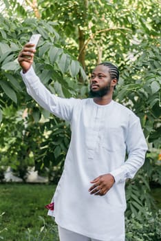 Happy young African American man in dashiki ethnic clothes taking selfie on brick wall background. Millennial generation student and youth