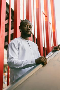 Cheerful male tourist portrait dress in white wear dashiki ethnic smiling at city street or small town background. African American travel model have free time. Millennial generation and gen z people.