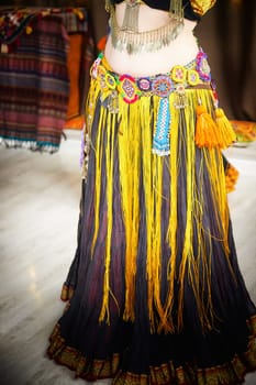 Diverse group of women wearing vibrant, multi-colored dress and tassels dancing tribal on ethnic celebratory event