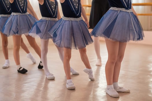 Children's ballet school. Close-up of the feet of five little ballerinas and their choreographer