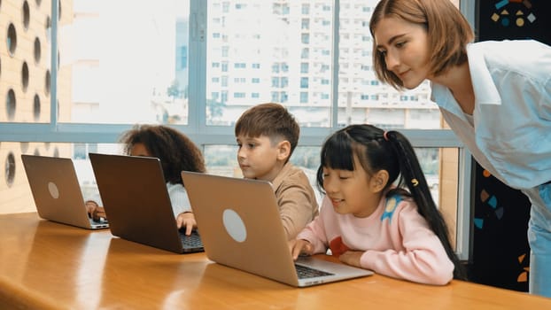 Smart teacher teaching and looking student using laptop at classroom. Professional instructor explained about programing engineering code or prompt while studying and learning program. Erudition.