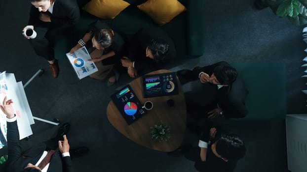 Top down view of business people listen businessman present idea while making decision. Group of diverse team making a decision to invest start up project while hold tablet display graph. Directorate.