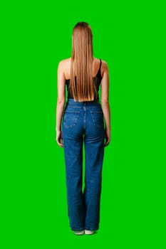 Woman in blue jeans with long hair on green background back view in studio