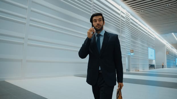 Professional leader walking to office while calling his business team about startup project. Handsome male leader report about marketing plan by using phone while going to meeting room. Exultant.