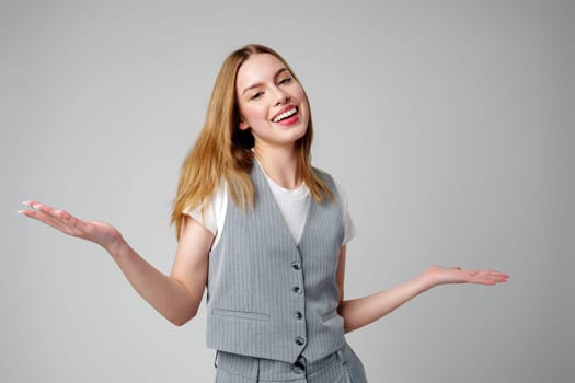 Joyful Young Blonde Woman Smiling against gray background in studio
