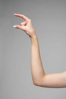 Female hand gesturing sign against gray background close up