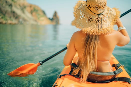 Woman in kayak back view. Happy woman with long hair in a swimsuit and hat floating in kayak on the sea. Summer holiday vacation. Summer holidays vacation at sea