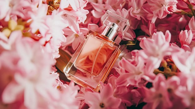 Perfume bottle in flowers, fragrance on blooming background, floral scent and cosmetic product idea