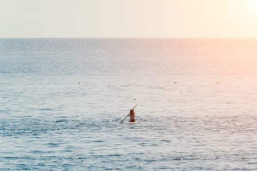 Sea woman sup. A happy positive woman in hat with family relaxing in sea, aerial back view of family on SUP board floating on calm water. Active lifestyle at sea. Summer vacation. Slow motion