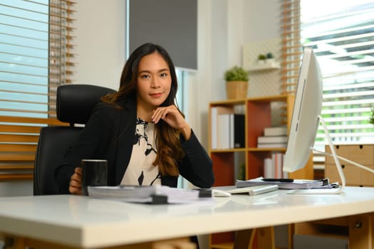 Portrait of beautiful female entrepreneur sitting in her office and looking at camera.