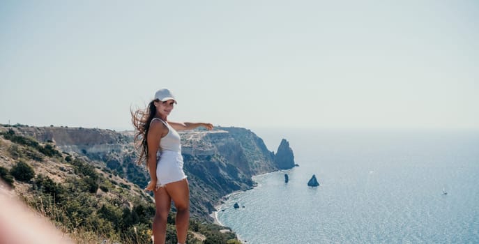 Woman travel sea. Young Happy woman in a long red dress posing on a beach near the sea on background of volcanic rocks, like in Iceland, sharing travel adventure journey