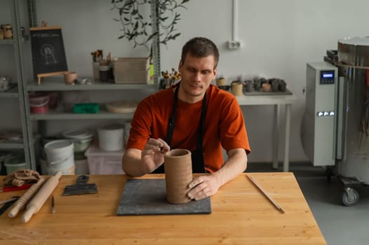 Potter sculpts a patterned cylinder from clay
