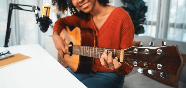 Host channel in musician of young African American playing guitar along with singing, broadcasting on smartphone in studio. Decoration of equipment headsets and recording microphone. Tastemaker.