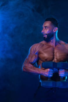 Athlete bodybuilder in neon colors. Fit man posing on black background. Sports concept. Bodybuilding competition. Download, high resolution, photo