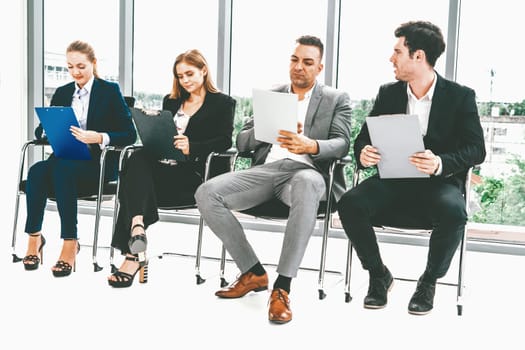 Businesswomen and businessmen holding resume CV folder while waiting on chairs in office for job interview. Corporate business and human resources concept. uds