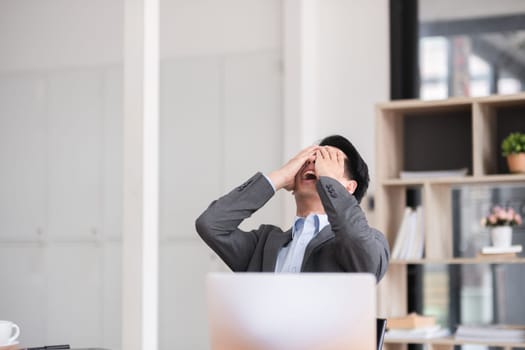 Unhappy young businessman feeling bored or disappointed while sitting in the office Distracted male employee feeling tired from monotonous work.