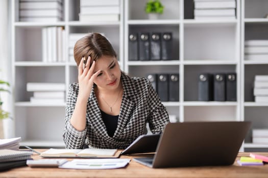 Young businesswoman has problems with her work in the office Feeling stressed and unhappy, showing a serious expression.