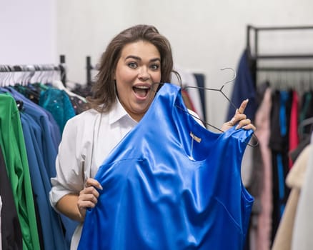 A fat woman chooses clothes in a plus size store