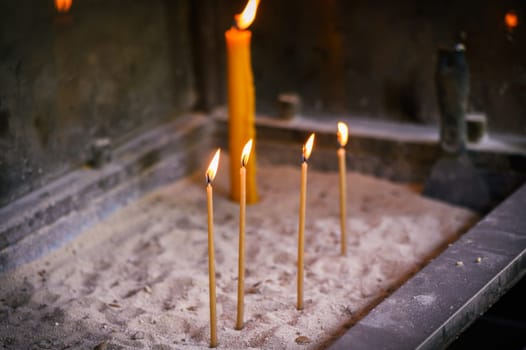 Close-Up of lighted candles inside a church.