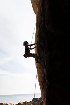 A woman is climbing a rock wall with a rope. The image has a mood of adventure and excitement