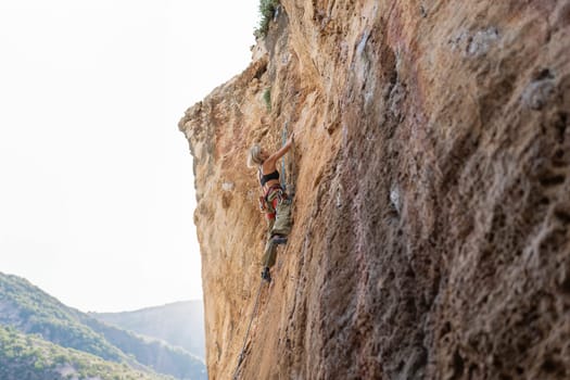 A woman is climbing a rock wall. The photo is in black and white