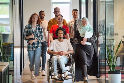 A diverse group of young business people congregates within a modern startup's glass-enclosed office, featuring inclusivity with a person in a wheelchair, an African American young man, and a hijab muslim woman