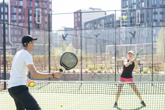 young woman playing Padel Tennis with partner in the open air tennis court. High quality photo