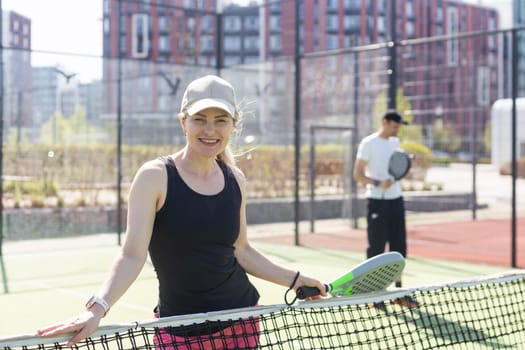 hands of a woman paddle player is holding balls and the racket at the background at the beginning of the match outdoors . High quality photo